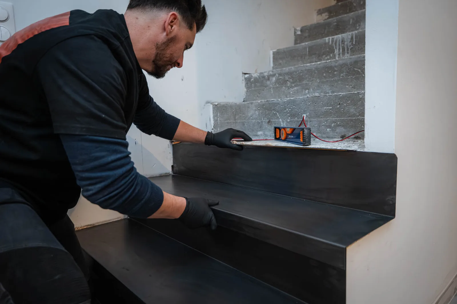 Contrôle au niveau d'une coque d'acier noir posée sur une marche d'escalier béton